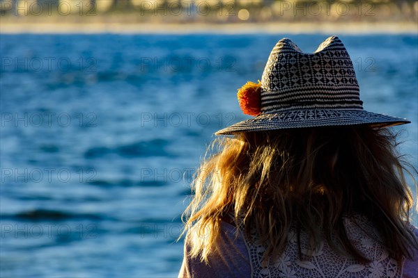 Woman with flower hat looking at Ipanema beach and city during afternoon