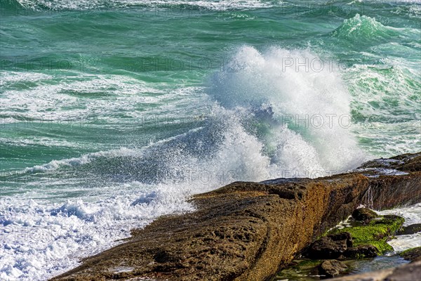 Wave breaking over rocks with water splashing in the air on a rough sea day in Rio de Janeiro