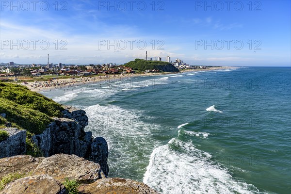 Crowded beach and rocks on a beautiful sunny day in the summer of Torres city on the coast of Rio Grande do Sul state