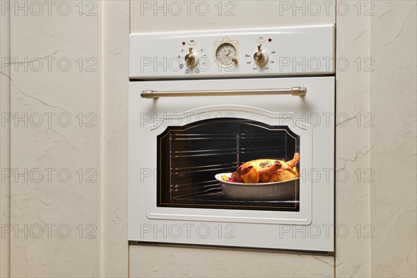 Process of baking food in oven. Whole chicken in ceramic casserole inside the oven