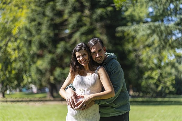 Pregnant woman posing with her partner outdoors