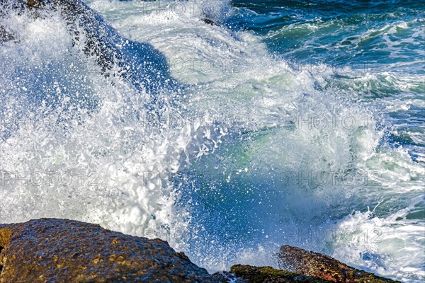 Wave crashing against the rocks with sea water splashing in the air