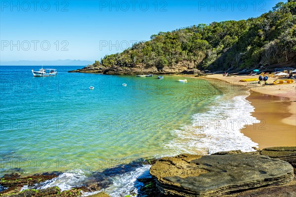 Paradise beach with colorful transparent waters surrounded by stones and vegetation in the city of Buzios