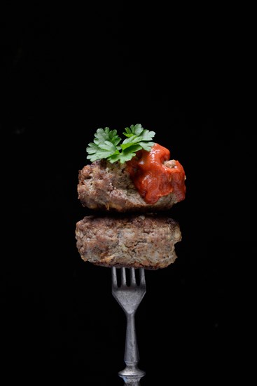 Two homemade meatballs on fork