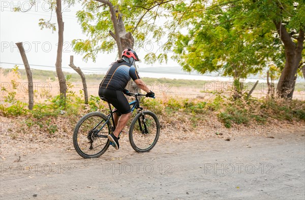 Fat cyclist on a dirt road surrounded by trees