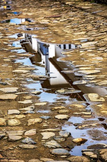 Reflections of an old colonial style house in a puddle in the cobblestone streets of the historic city of Paraty in Rio de Janeiro