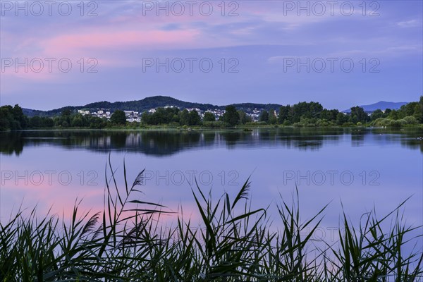The Great Roetelsee Pond in the Roetelseeweiher bird sanctuary after sunset. The sky is reflected in the calm lake surface. In the background the town of Cham