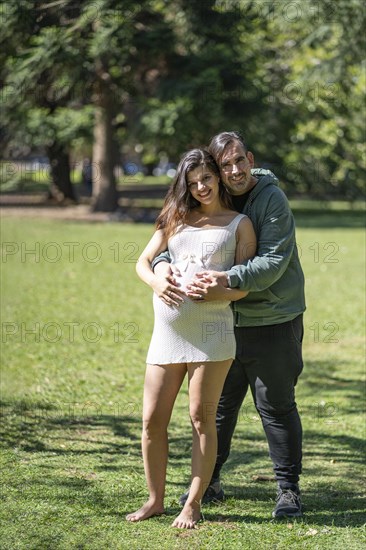 Pregnant woman posing with her partner outdoors