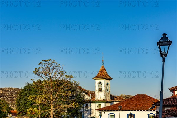 Baroque church tower with bell rising through the trees and roofs of the historic town of Diamantina in Minas Gerais