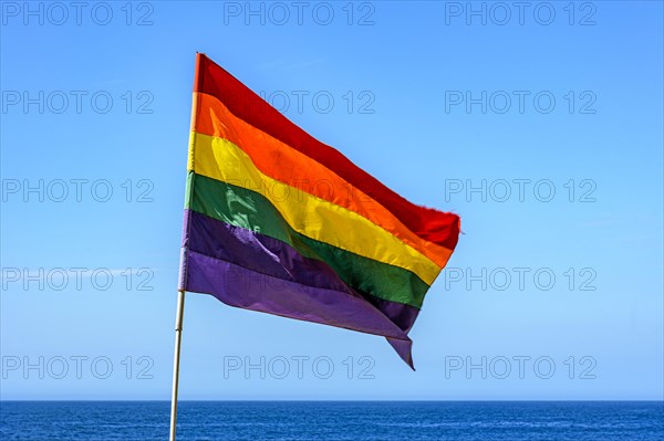 Lbgtq+ flag in the blue sky of the city of Rio de Janeiro