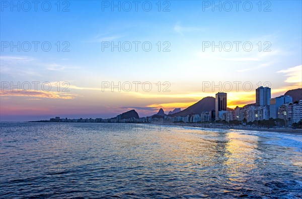 Copacabana beach sunset in Rio de Janeiro with the light coming from behind the buildings and hills