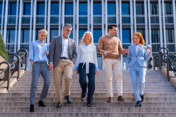 Cheerful group of coworkers outdoors in a corporate office area walking down some stairs going to work