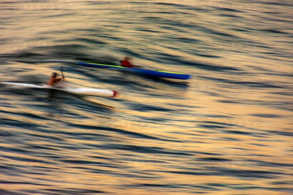 Canoeing on the wave at sunset in the sea of the city of Salvador in Bahia with blurred motion and unrecognizable people