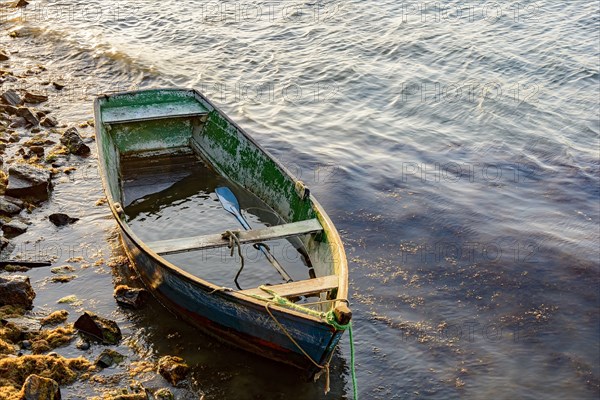 Old wooden fishing boat floating over seawater at sunset