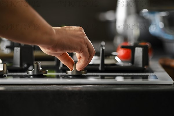 Hand switching on gas on a stove