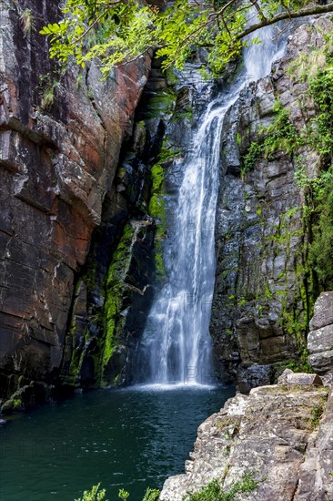 Waters of waterfall called Veu da Noiva between moss covered rocks and the vegetation of an area with nature preserved in the state of Minas Gerais