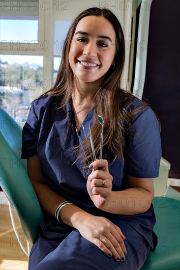 Front view of professional female dentist keeping dental tools