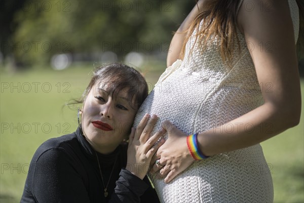 Woman listening to his pregnant girlfriend's tummy