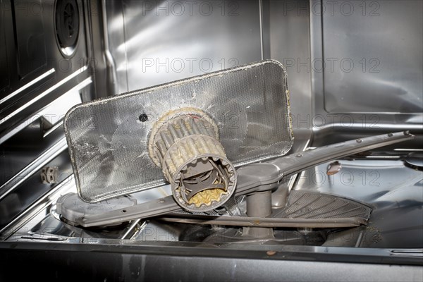 A heavily soiled drain strainer in a dishwasher