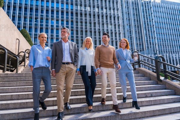 Cheerful group of coworkers outdoors in a corporate office area going down some stairs going to work