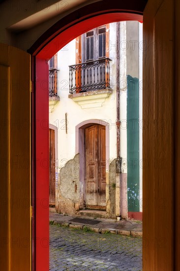 Old door in colonial architecture deteriorated by time seen through another door also old and with the same architecture in the city of Ouro Preto