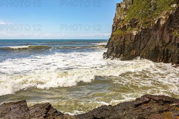 Waves crashing against a large rock wall in the city of Torres in the state of Rio Grande do Sul