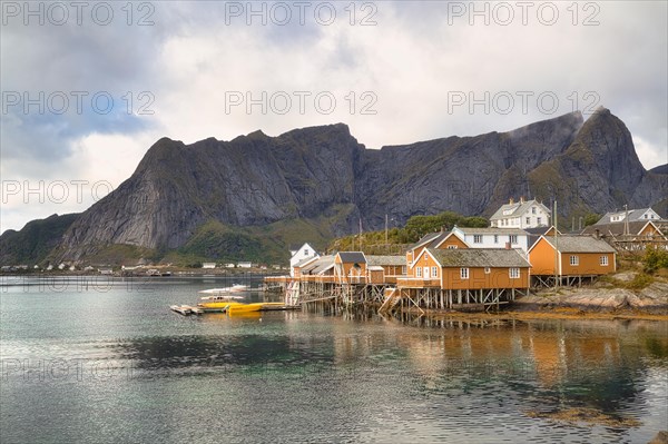 Yellow rorbuer cabins by the fjord with mountains in the background