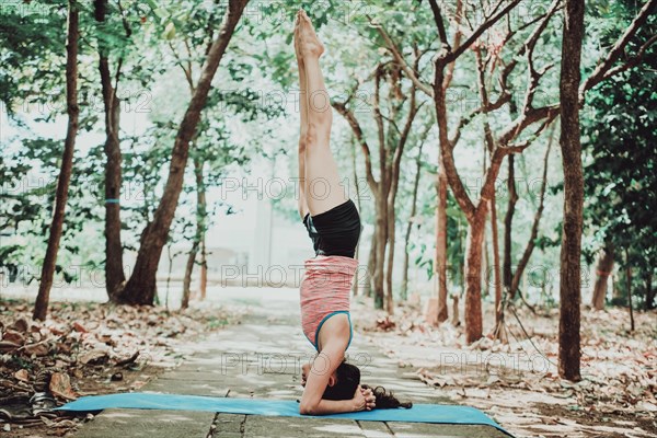 Young woman doing headstand yoga outdoors. Spiritual girl practicing yoga sirshasana outdoors