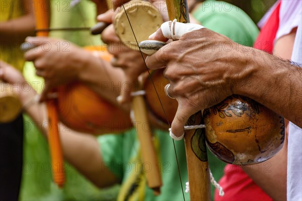 Hands of a musician playing an Afro Brazilian percussion musical instrument called a berimbau during a capoeira performance in the streets of Brazil