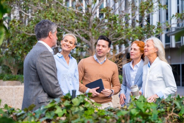 Talking next to a green area of the business area. Group executives or businessmen and businesswoman in a business area