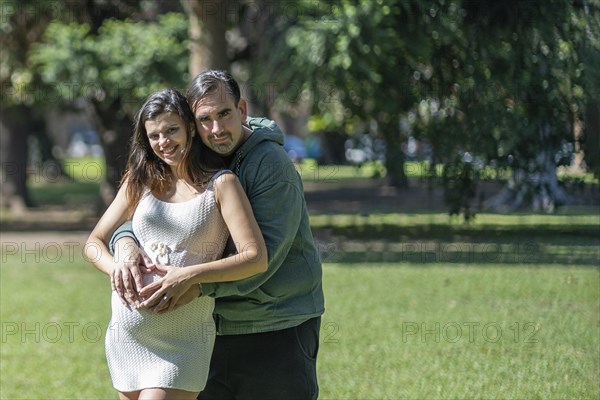 Pregnant woman posing with her partner outdoors