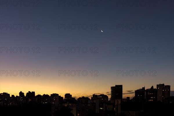 Skyline of Porto Alegre at dusk with the moon in the sky with buildings silhuette