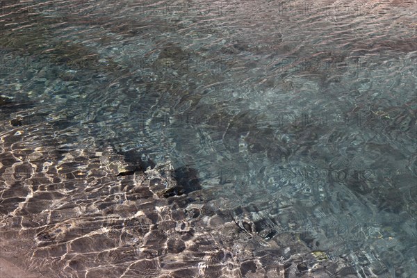 Sun reflections create an abstract pattern on the surface of a crystal clear body of water