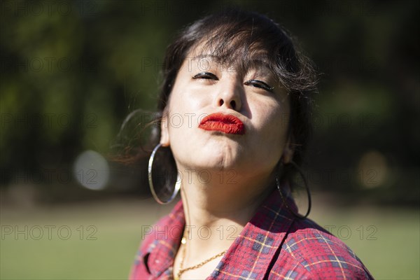 Portrait of andean woman posing in a park. Model striking a pose in a park. Woman blowing a kiss