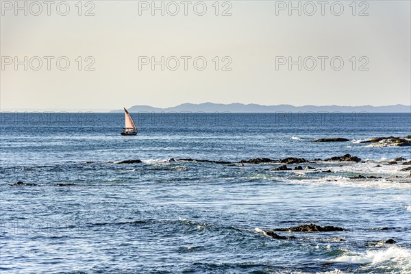 Rudimentary fishing boat sailing through the calm waters of Todos os Santos Bay in Slavador city in Bahia during sunset