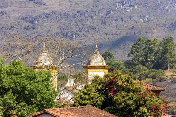 One church tower of the many historic churches in baroque and colonial style from the 18th century amid the hills and vegetation of the city Ouro Preto in Minas Gerais