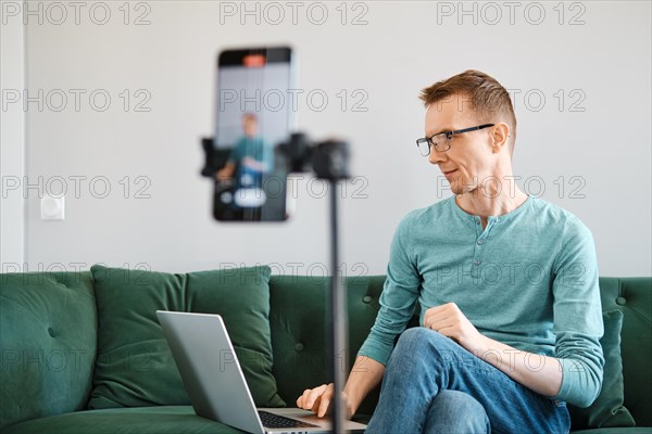 Middle-aged man leads an online broadcast and answers questions from the audience from home