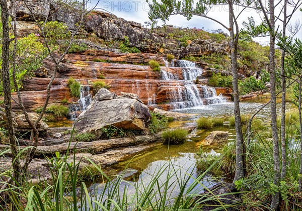 Waterfall and lake among the vegetation with mountains in background on Biribiri environmental reserve on Diamantina