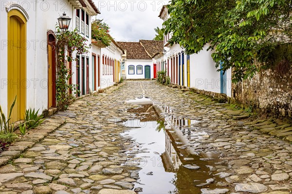 Cobblestone street with colorful colonial houses and reflections in the puddles in the historic city of Paraty