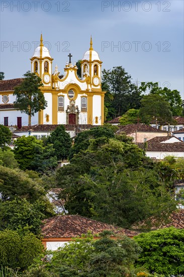 Historic colonial-style church surrounded by houses and greenery in the city of Tiradentes in Minas Gerais