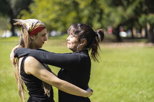 Couple of women hugging in a park looking at each other with love