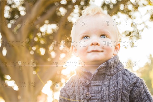 Smiling blonde baby boy outdoors at the park