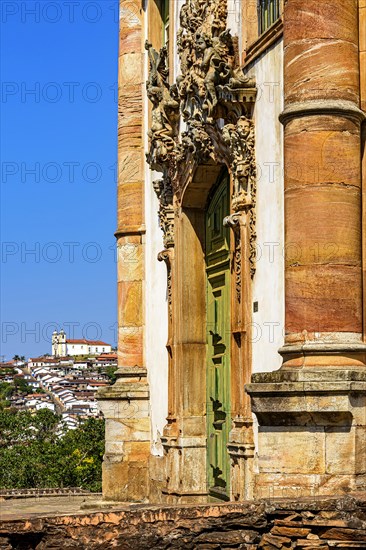 Old door and facade of historic baroque church with the city of Ouro Preto in Minas Gerais in the background