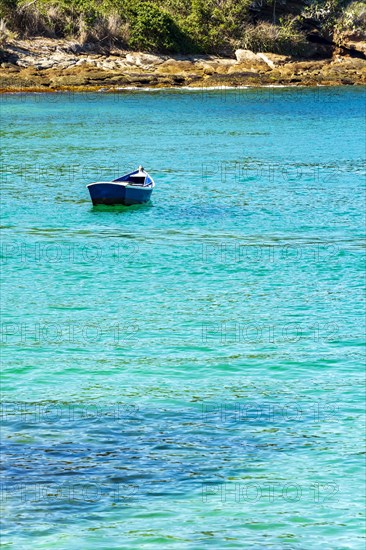 Old wooden fishing boat floating on the colorful and transparent waters of the sea of Buzios in the state of Rio de Janeiro