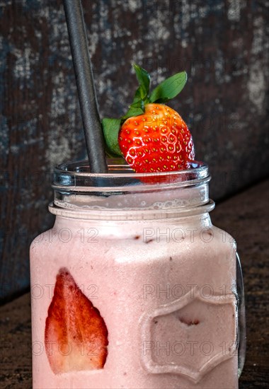Strawberry Shake in Glass with Straw on Brown Background