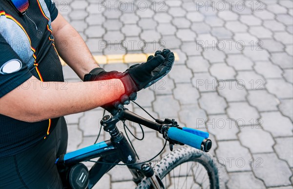 Cyclist man with hand pain outdoors. Close up of cyclist with arthritis outdoors