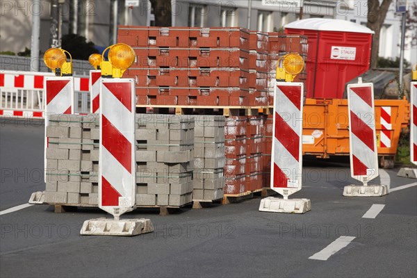 Stacked red building blocks with barrier beacons on a construction site for a cycle path
