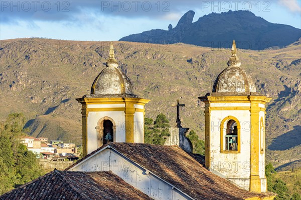 Historic church tower in baroque architecture with mountains in the background in Ouro Preto