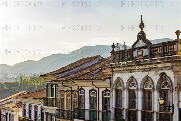 Facades of houses in colonial architecture in an old street in the city of Ouro Preto with the mountains in the background
