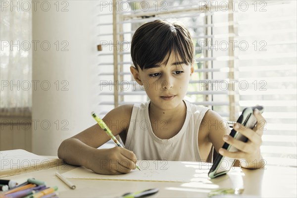 Child sitting at home with pen in hand drawing and coloring. Process of learning and the creative development of children